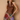 A woman posing in a brown satin halter top and a colorful patchwork print skirt against a textured beige wall.