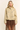 A woman modeling a beige cropped jacket with silver rhinestone embellishments, paired with a brown sheer tiered skirt, against a plain cream background.