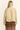 A woman shown from the back wearing a light beige cropped jacket and a brown sheer tiered skirt against a plain off-white background.