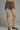 Brown polka dot shorts with lace trim worn by a person on a gray background