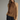 A woman modeling a sleeveless high-neck satin top in warm brown with a lace hem detail, paired with dark wide-leg pants, against a plain gray studio background.