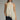 Woman wearing a beige halter top with lace trim and black pants on a gray background