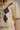 A close-up of a cream-colored short-sleeve knit cardigan with a navy blue and white argyle pattern on the front, worn by a model.