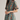A woman modeling a short-sleeve high-neck mini dress with a teal background and a vertical floral print in orange, red, and green, set against a plain light gray studio background.