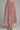 A pink and burgundy polka dot midi skirt with a gingham texture, shown on a model from the waist down wearing gold flat shoes against a neutral gray background.