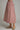 A pink and red gingham midi skirt with a red polka dot pattern, shown on a model wearing gold flat shoes against a neutral gray background.