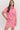 Woman wearing a pink outfit with red patterns on a white background