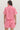 Person wearing a pink outfit with shell pattern on a plain background