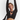 A woman with her arms raised overhead wears a sheer black long-sleeve crop top with horizontal slub texture. She is posing against a clean white studio background, with a black shoulder bag and black headphones around her neck.