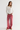 A woman modeling a white long-sleeve top with lace sleeves and pink wide-leg pants, standing against a plain light gray studio background.