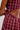 Close-up of a person wearing a burgundy plaid crop top and matching bottoms, showing the side button detail and fabric texture.