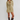 A woman modeling a light olive-beige knit mini dress with a lace-up keyhole neckline, paired with dark brown knee-high leather boots, against a plain light gray studio background.
