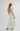 Woman wearing a light green dress with thin straps on a white background