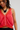 Woman wearing a red sleeveless top with lace details on a plain background