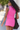 Woman wearing a pink tennis outfit with a white wall and blurred background