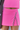Person wearing a pink skirt with a white stripe on a plain background