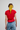 Person wearing a red top and blue jeans with a yellow bandana in their hair on a plain background
