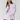 A model wearing a light lavender long-sleeve boatneck t-shirt, dark purple athletic shorts, and a cream-colored knit beanie hat, posed against a solid light gray studio background.