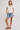 Woman wearing a white shirt and denim shorts on a plain background