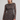 A woman modeling a long-sleeve brown mini dress with a blue and pink fish pattern, set against a plain light gray studio background.