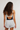 A woman shown from the back wearing a dark navy and white strappy open-back tank top with light gray heathered shorts, set against a plain light gray studio background.