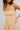 Woman wearing a yellow and white striped dress against a plain background