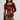 A woman modeling a long-sleeve scoop-neck top in dark burgundy with a large red, orange, and yellow floral print on the front, paired with an olive green mini skirt and a patterned belt, against a light gray studio background.