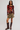 A model stands against a light gray studio background wearing a long-sleeve scoop-neck top with a dark red and orange floral print, an olive green mini skirt, and dark brown knee-high boots.