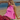 Person sitting on a beach wearing a pink top and striped pants.