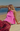 Person sitting on a beach wearing a pink top and striped pants.