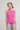 Woman wearing a pink sleeveless top and striped pants on a plain background