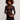 A model with curly brown hair wearing a sheer black mesh long-sleeve top over a black bralette, paired with a black denim mini skirt, against a plain light gray studio background.