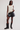 Woman wearing a cream sleeveless top, black leather shorts, and black boots on a white background