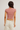 Person wearing a pink crop top and light-colored pants against a plain background