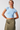 Woman wearing a light blue crop top and green skirt on a white background