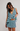 Woman wearing a floral ruffled dress against a plain background