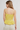 Woman wearing a yellow checkered top against a plain background