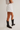 Person wearing a white denim skirt and black cowboy boots on a plain background