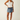 Woman wearing a white tank top and denim skirt on a plain background