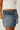 Person wearing a blue denim skirt and white top on a plain background