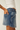 Person wearing a blue denim skirt with a white background