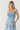 Woman wearing a strapless blue and white patterned dress on a plain background