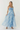 Woman wearing a blue tie-dye strapless dress on a white background