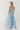 Woman wearing a blue tie-dye strapless dress on a white background
