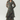 A woman modeling a long-sleeve, high-low floral midi dress with a tie waist, ruffled layers, and a sheer mesh fabric, paired with black pointed-toe heels against a light gray studio background.