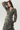 A woman modeling a long-sleeve wrap dress with a tie waist and a green base covered in a red and dark floral print, photographed against a plain light gray studio background.