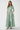 Woman wearing a light green dress with a belt on a white background