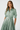 Woman wearing a green dress with a belt on a white background