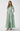 Woman wearing a long green dress with a belt on a white background