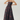 A strapless floor-length gown with a sweetheart neckline, fitted bodice, and full skirt, featuring a dark floral pattern in black and deep burgundy. The model is standing against a light gray studio background.